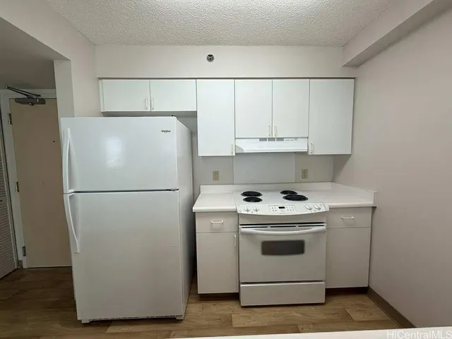 a white refrigerator freezer and a stove sitting inside of a kitchen with granite countertop white cabinets and a refrigerator