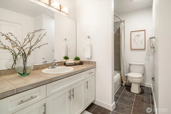 a bathroom with a granite countertop toilet sink and mirror