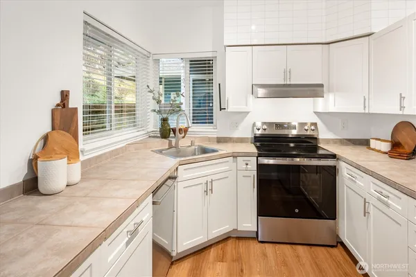a kitchen with a stove a sink and a white wooden cabinets