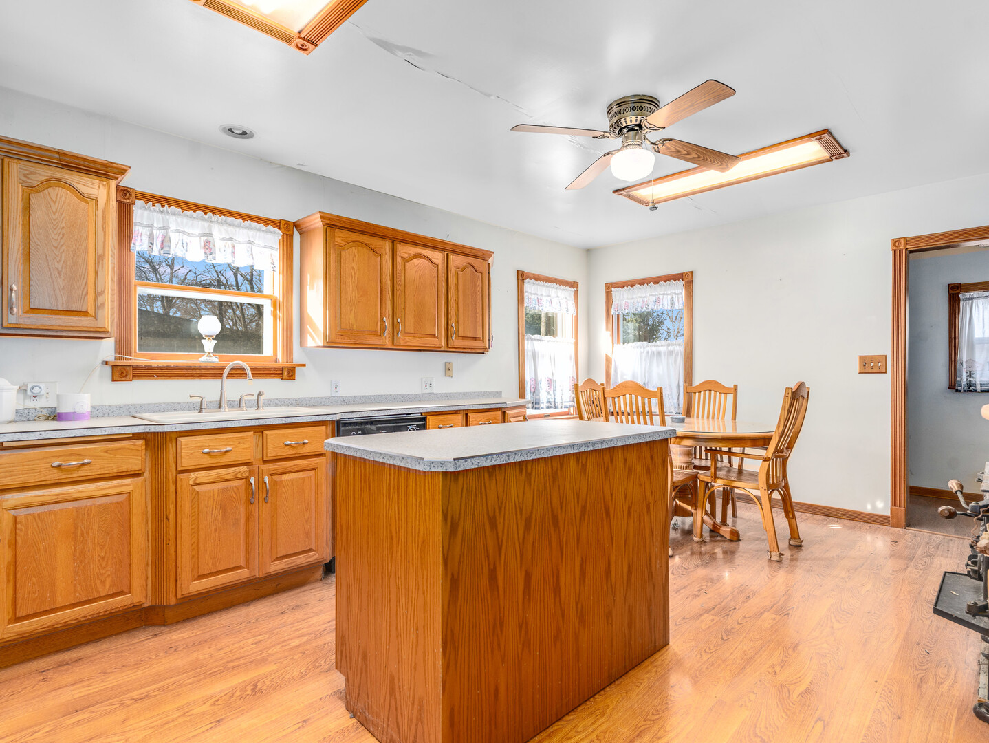 17902 Locust Street Lansing, IL 60438 - Photo 6 of 15 a open kitchen with stainless steel appliances granite countertop a stove top oven a sink dishwasher a dining table and chairs with wooden floor