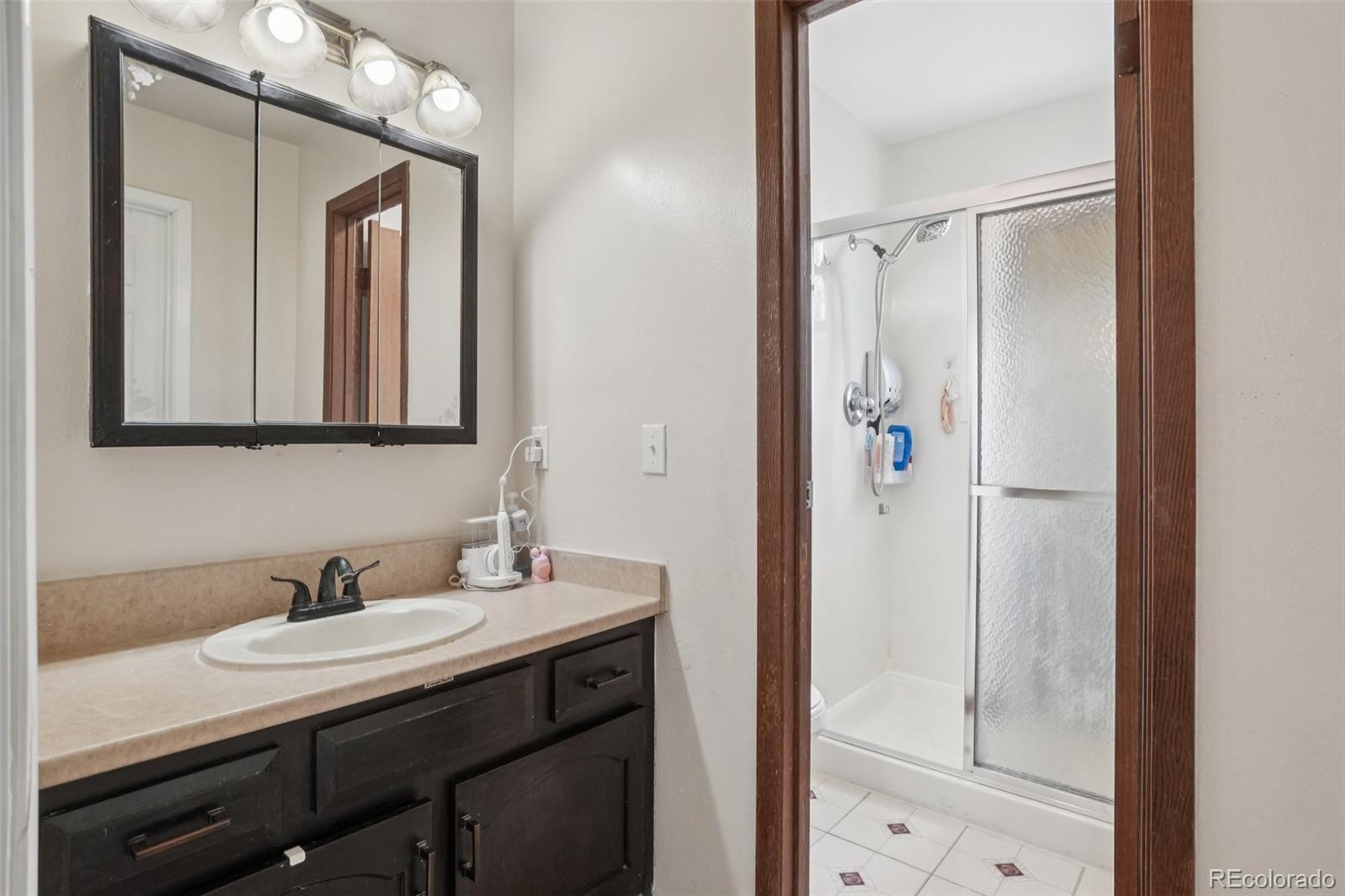 16646 East Rice Circle Aurora, CO 80015 - Photo 22 of 39 a bathroom with a sink a mirror a vanity and a shower