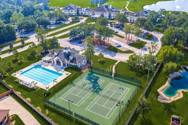 an aerial view of a tennis ground and a cars park side of the road