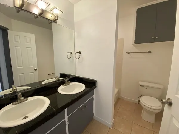 a bathroom with a granite countertop sink toilet and a mirror