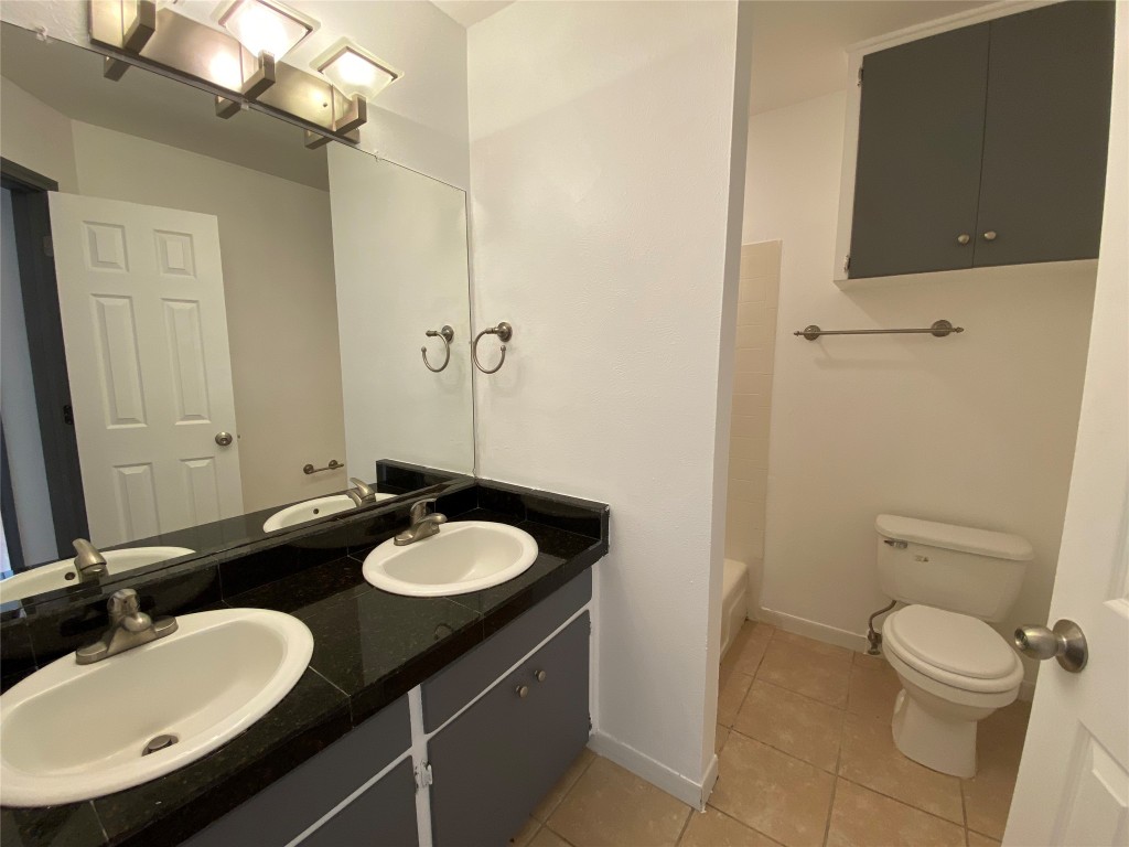 4306 Avenue A, Unit 113 Austin, TX 78751 - Photo 13 of 16 a bathroom with a granite countertop sink toilet and a mirror