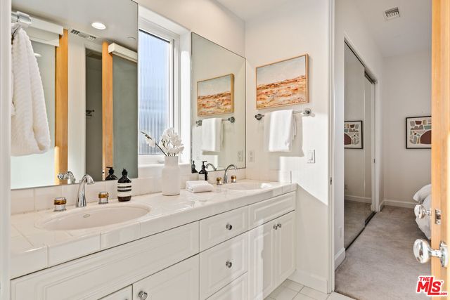 a bathroom with double vanity sink a mirror a window and a shower