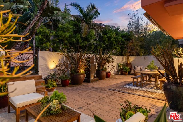 a view of a patio with table and chairs potted plants and large tree