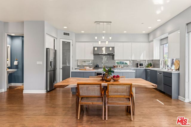 a kitchen with stainless steel appliances kitchen island granite countertop a dining table chairs and sink