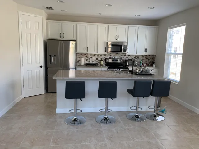 a kitchen with stainless steel appliances kitchen island granite countertop a refrigerator and cabinets