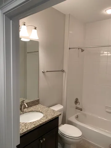 a bathroom with a granite countertop sink toilet a mirror and shower