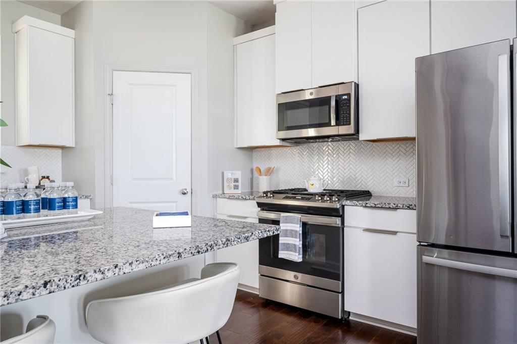1444 Ridgebend Way Southeast Mableton, GA 30126 - Photo 16 of 34 a kitchen with stainless steel appliances granite countertop a stove a microwave and a refrigerator