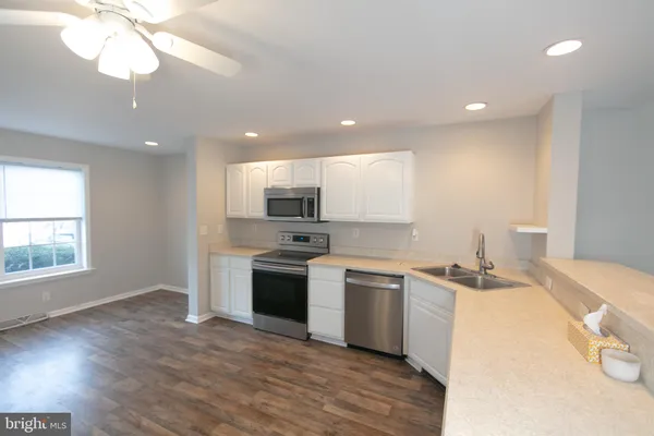 a kitchen with stainless steel appliances a sink a stove a refrigerator cabinets and a large window