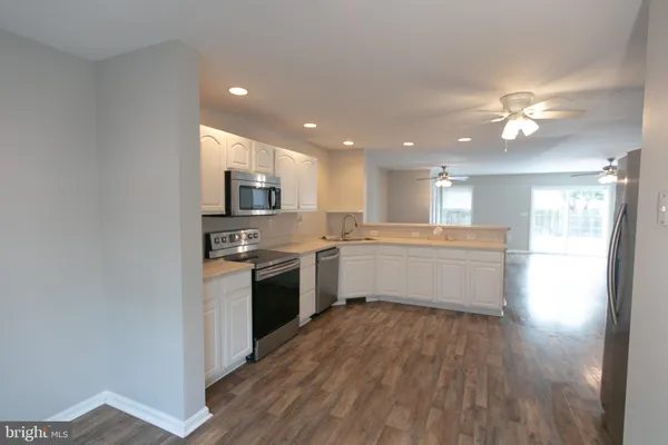 a large kitchen with a center island wooden floor and stainless steel appliances