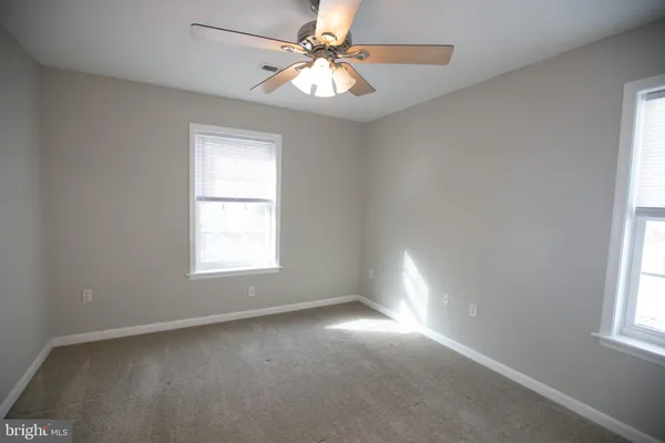 an empty room with windows and fan