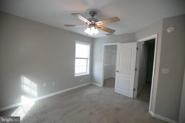 a view of an empty room with a ceiling fan and a window