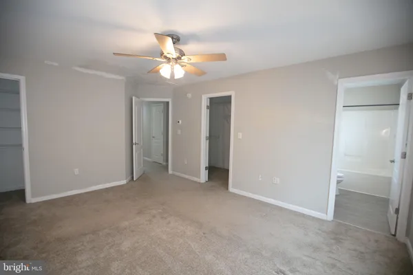 an empty room with closet and a chandelier fan