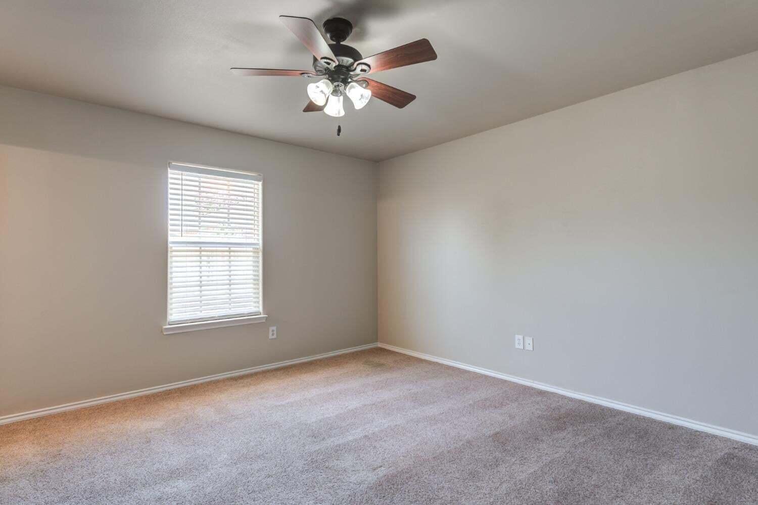 6554 92nd Street Lubbock, TX 79424 - Photo 12 of 17 an empty room with a chandelier fan and windows