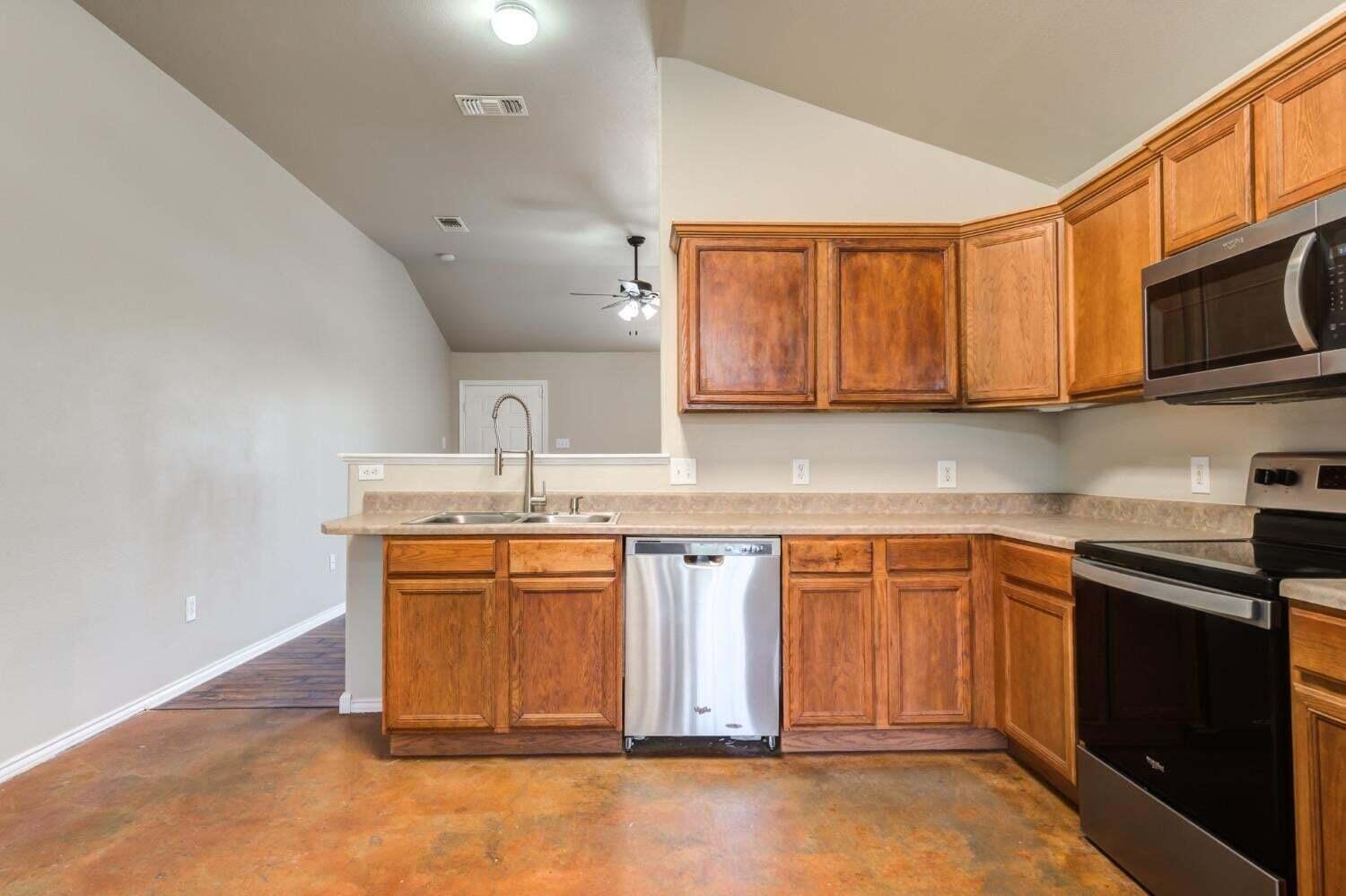 6554 92nd Street Lubbock, TX 79424 - Photo 7 of 17 a kitchen with stainless steel appliances granite countertop a sink stove and microwave