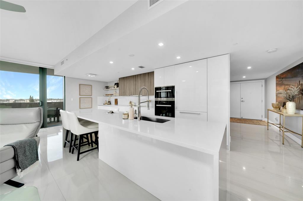 730 North Ocean Boulevard, Unit 405 Pompano Beach, FL 33062 - Photo 5 of 47 a large white kitchen with lots of counter space and furniture