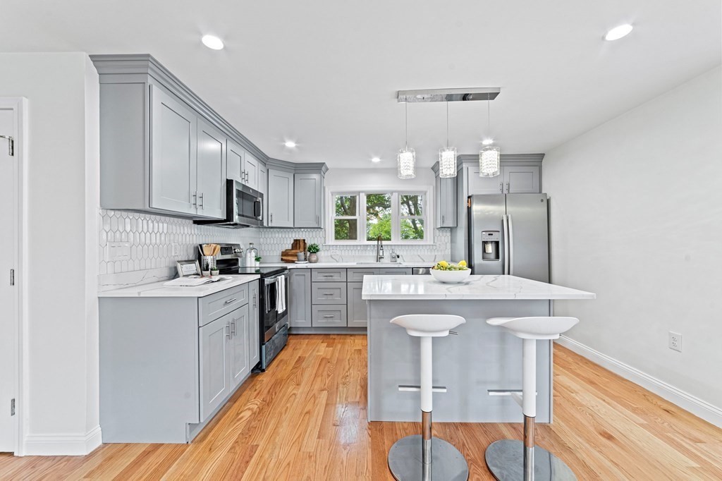 40 Howe Street Quincy, MA 02169 - Photo 17 of 42 a kitchen with stainless steel appliances granite countertop a stove top oven a sink dishwasher and white cabinets with wooden floor