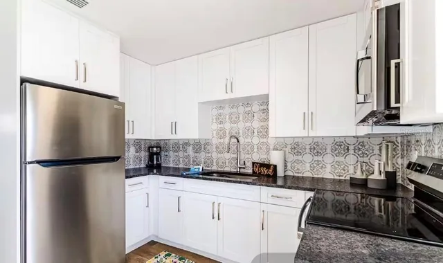a kitchen with stainless steel appliances a refrigerator sink and white cabinets