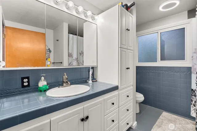 a bathroom with a granite countertop sink toilet and mirror