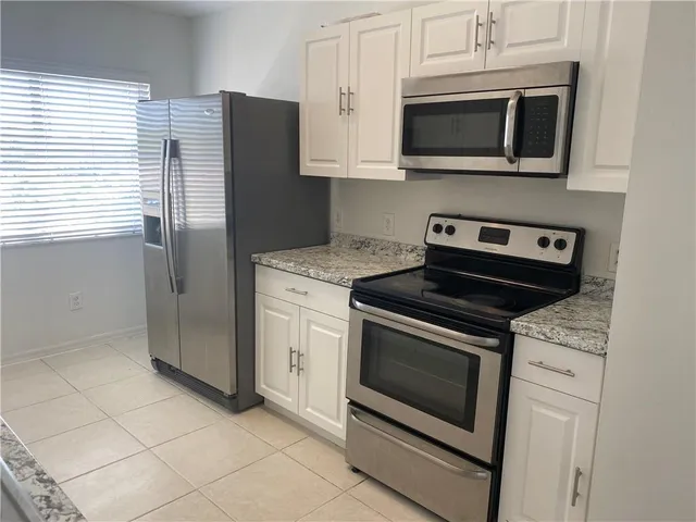 a kitchen with granite countertop cabinets stainless steel appliances and a window