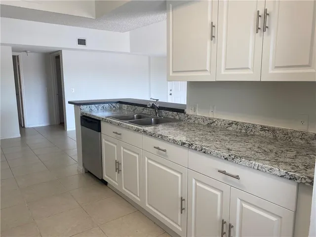 a kitchen with granite countertop white cabinets and a sink