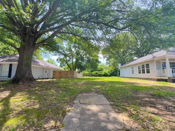 a view of a yard in front of a house with large trees