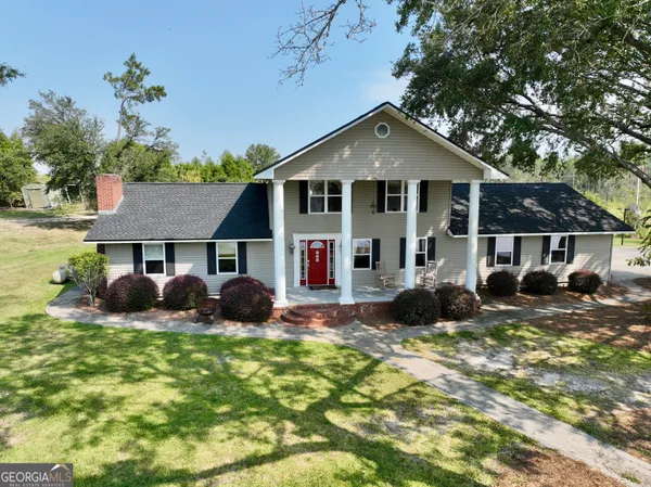 a view of a house with a big yard and large trees