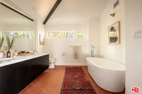 a spacious bathroom with a tub sink and mirror