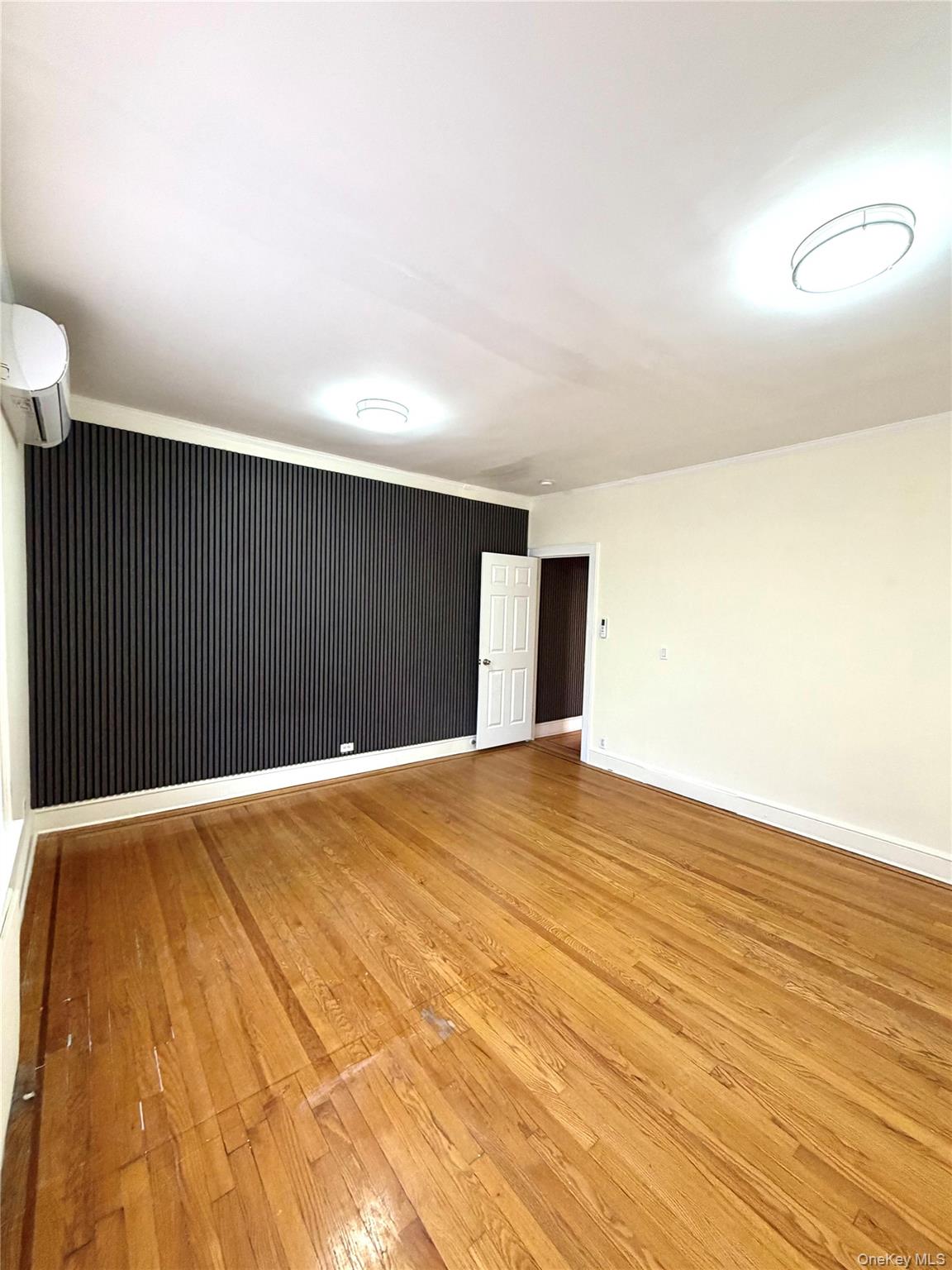 30-06 85th Street, Unit 2 Queens, NY 11370 - Photo 3 of 7 Huge bedroom or living room with light wood finished floors and a wall mounted AC