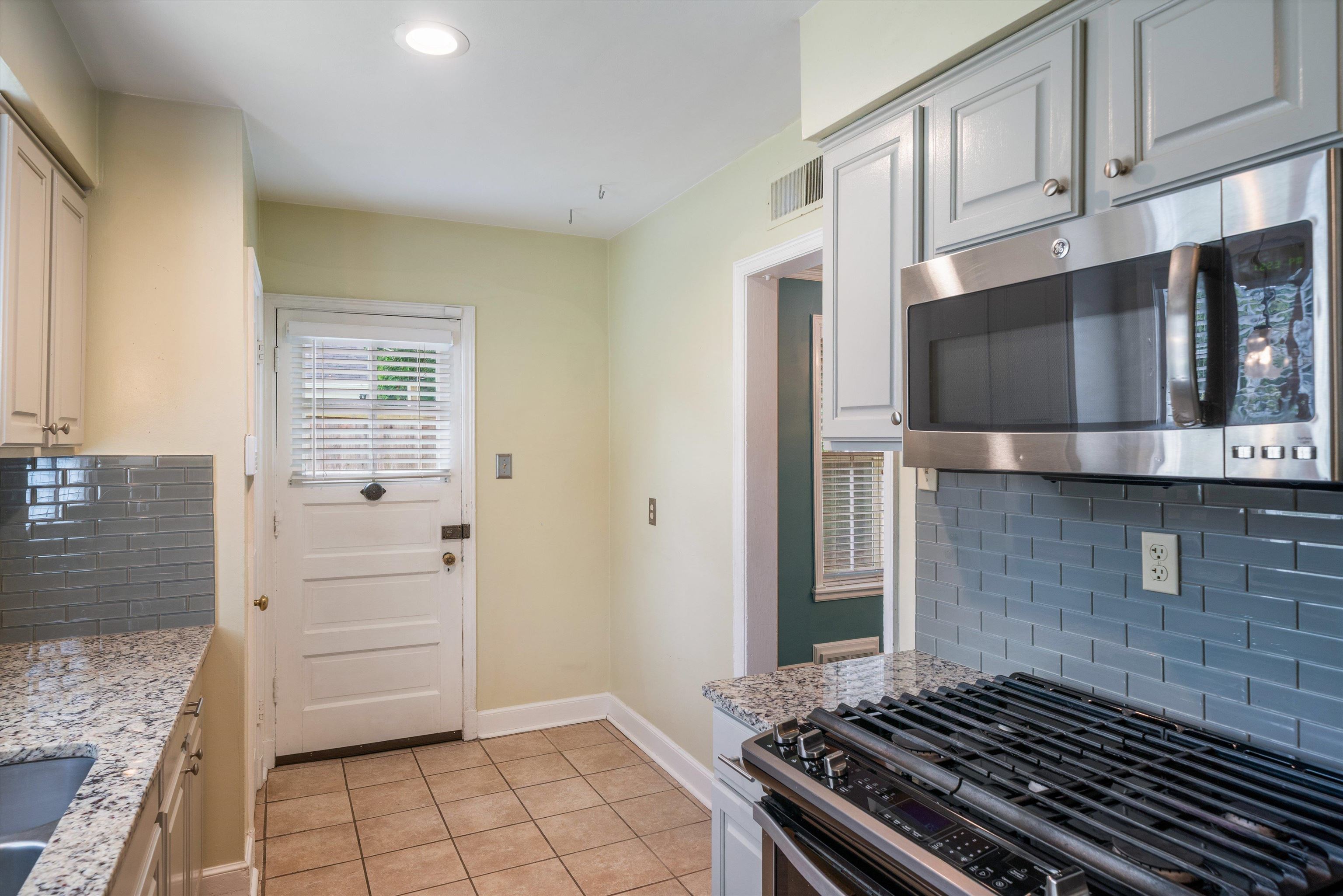 17 North Ashlawn Road Memphis, TN 38112 - Photo 11 of 28 Kitchen with tasteful backsplash, gas range oven, stainless steel microwave, light tile patterned floors, and light stone countertops