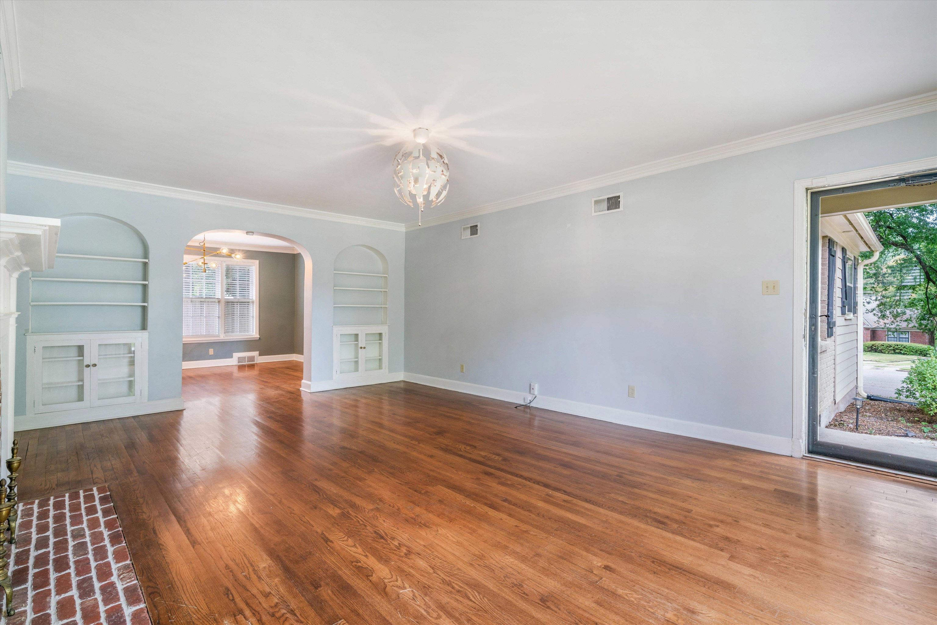 17 North Ashlawn Road Memphis, TN 38112 - Photo 5 of 28 Unfurnished living room featuring built in features, arched walkways, ornamental molding, and plenty of natural light