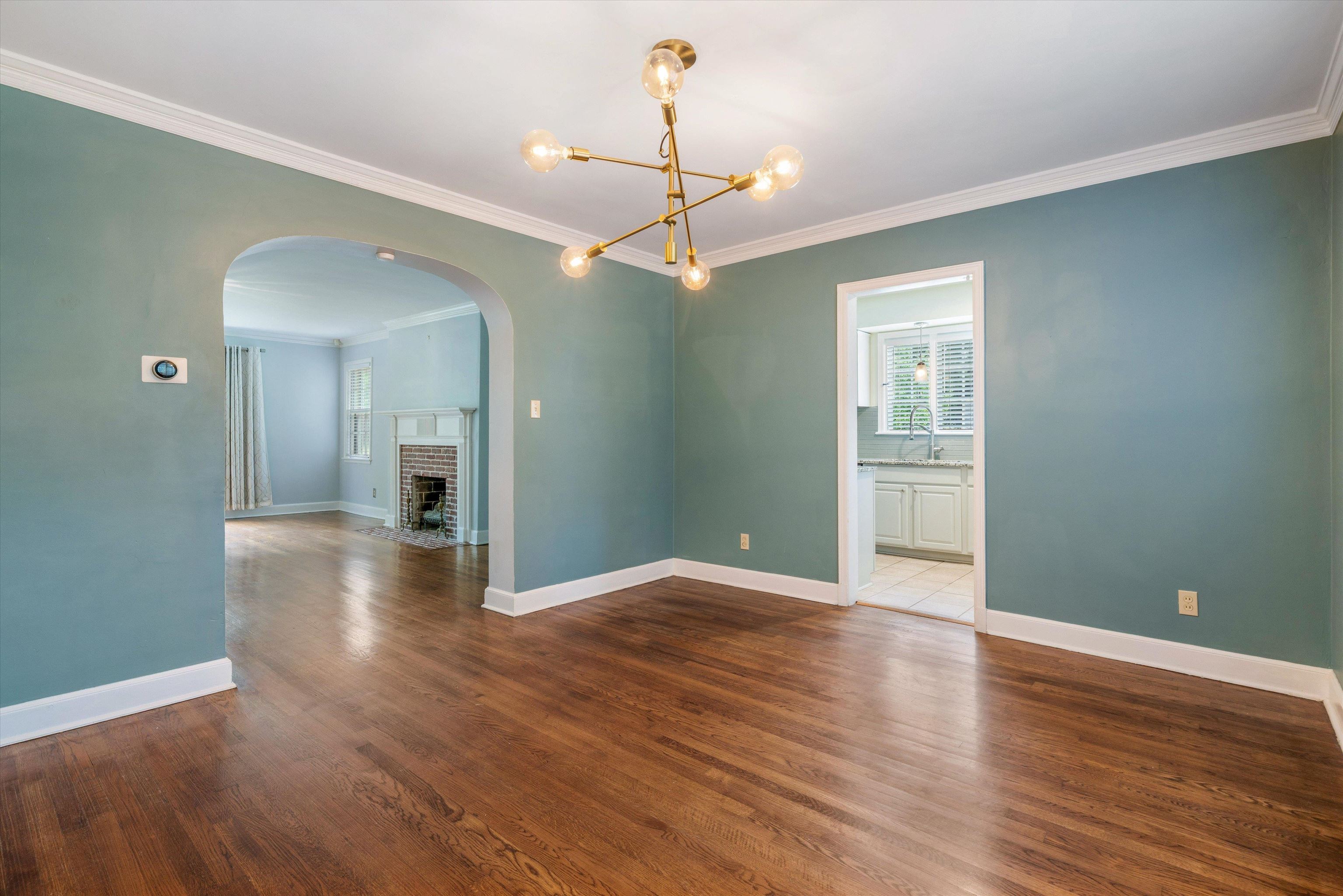 17 North Ashlawn Road Memphis, TN 38112 - Photo 8 of 28 Unfurnished dining area featuring crown molding, a fireplace, arched walkways, dark wood finished floors, and a chandelier