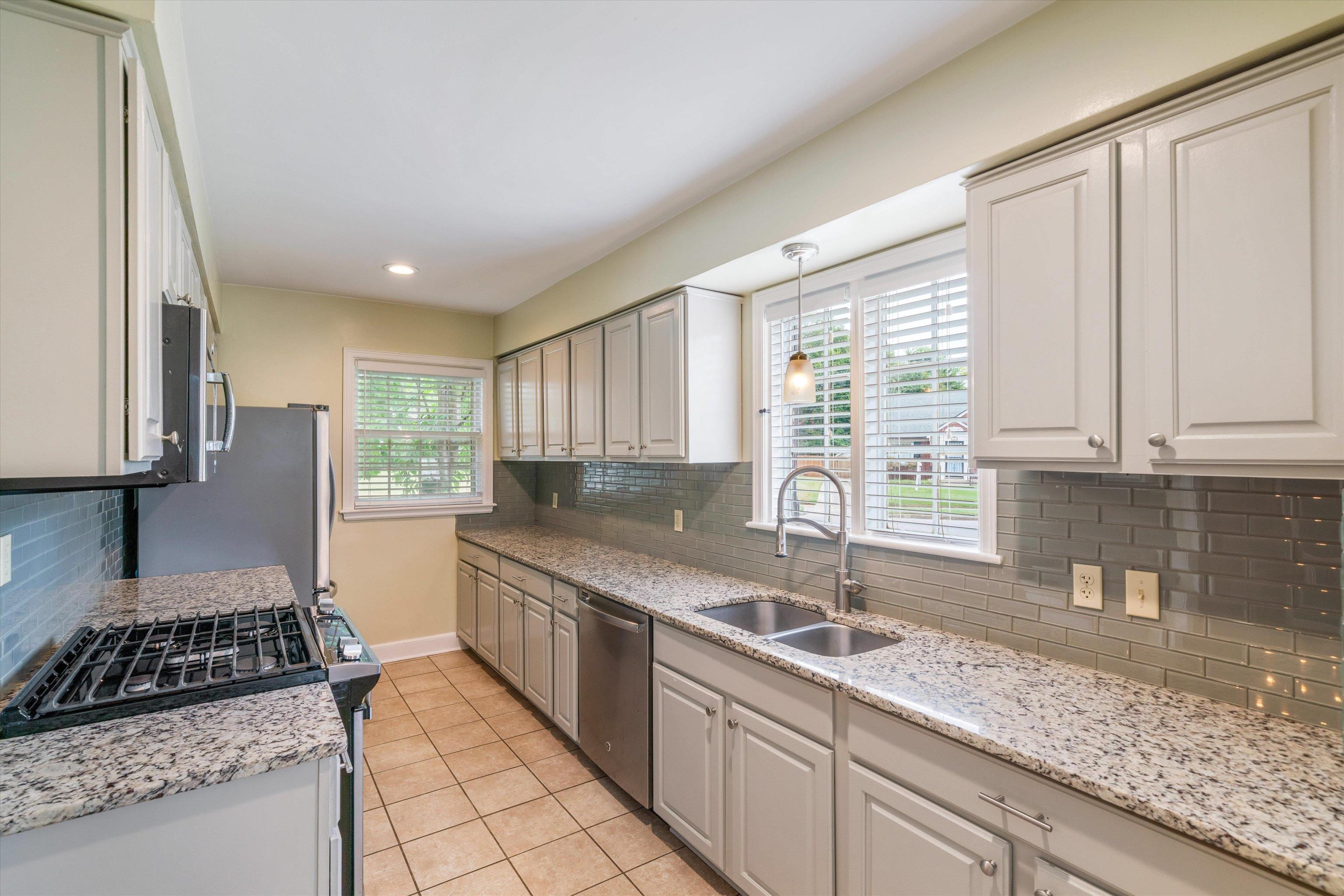 17 North Ashlawn Road Memphis, TN 38112 - Photo 9 of 28 Kitchen with backsplash, stainless steel appliances, light tile patterned floors, light stone counters, and pendant lighting