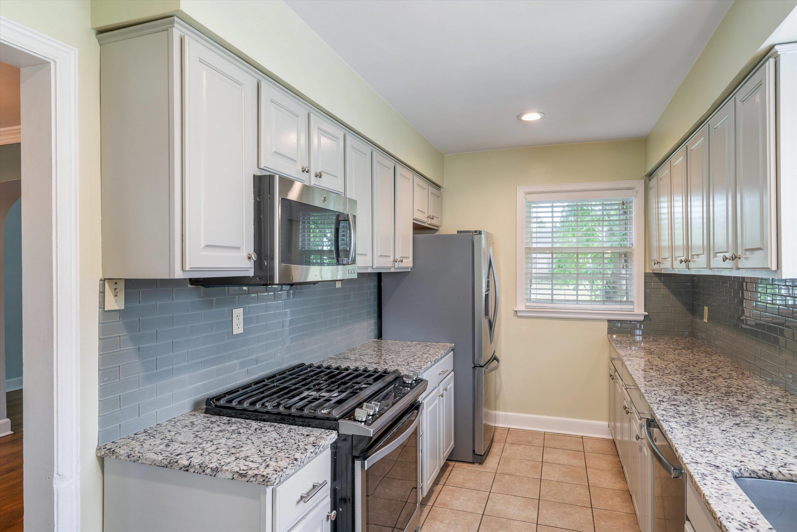17 North Ashlawn Road Memphis, TN 38112 - Photo 10 of 28 Kitchen featuring stainless steel appliances, tasteful backsplash, light tile patterned flooring, light stone counters, and recessed lighting