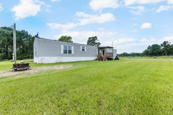 a view of a house with a big yard and a large trees
