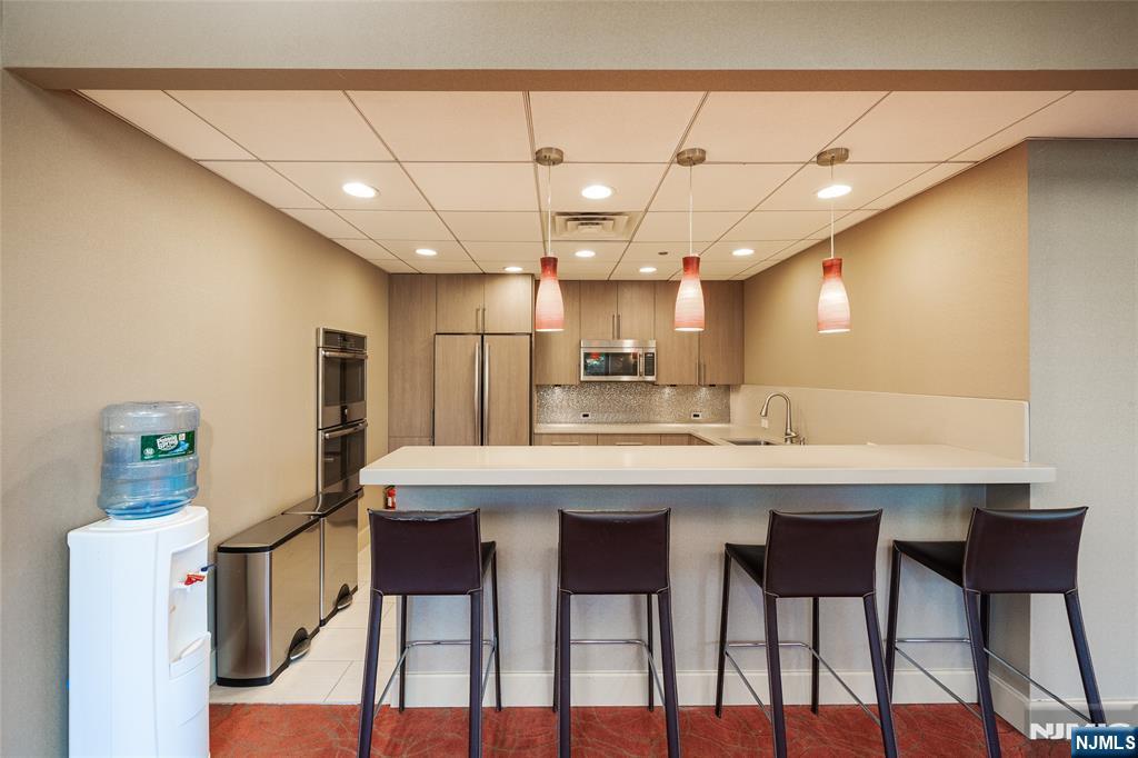 250 Gorge Road, Unit 23A Cliffside Park, NJ 07010 - Photo 27 of 41 a kitchen with kitchen island a dining table chairs and white cabinets