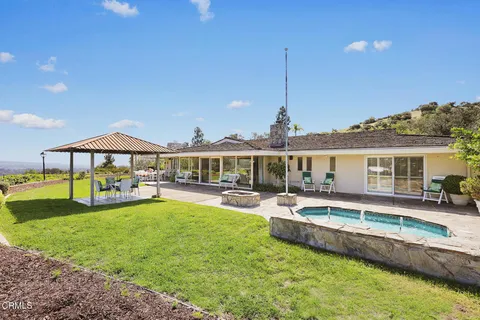 a view of a house with a big yard and large tree