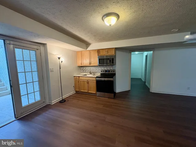 a view of kitchen with stainless steel appliances wooden floor and wooden cabinets
