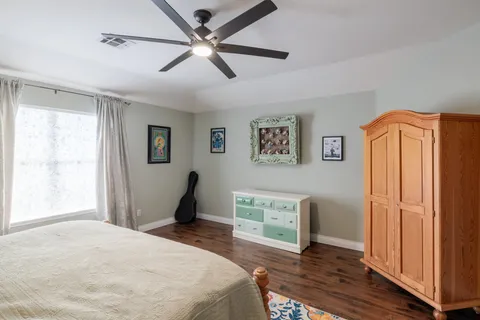 a bedroom with wooden floor closet and a ceiling fan