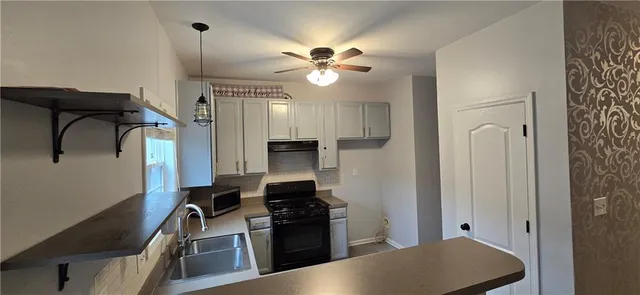 a kitchen with stainless steel appliances granite countertop a refrigerator a stove and a sink with wooden floor