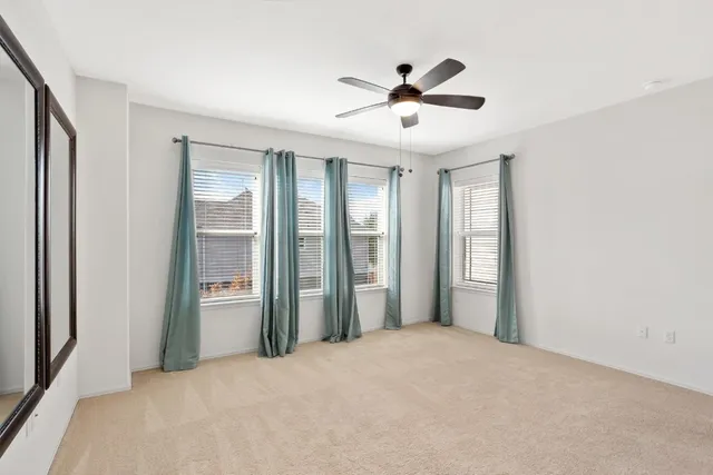 a view of a livingroom with a ceiling fan & windows
