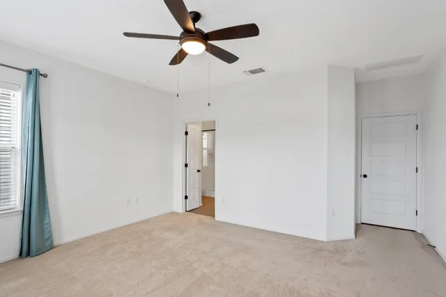 an empty room with a ceiling fan and a window