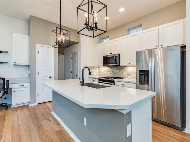 a kitchen with stainless steel appliances a table chairs refrigerator and microwave