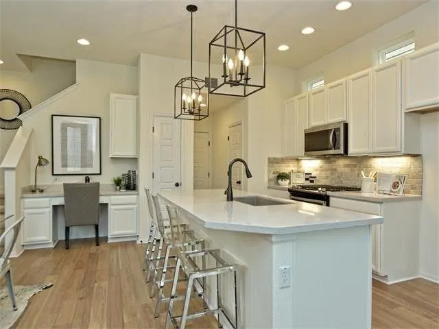 a kitchen with stainless steel appliances granite countertop a stove top oven a sink dishwasher a dining table and chairs with wooden floor