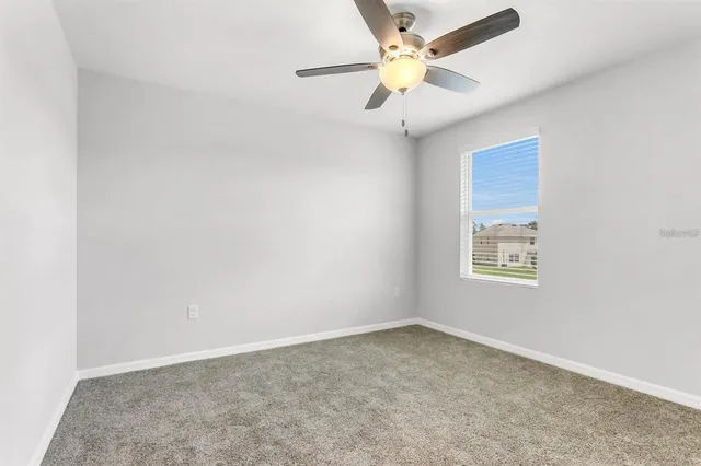 an empty room with a window and a fan