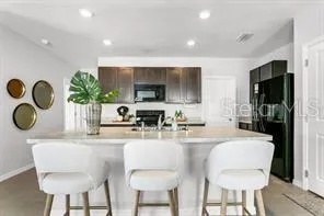 a kitchen with stainless steel appliances granite countertop a dining table chairs and a refrigerator