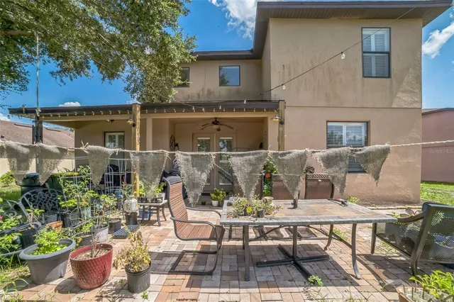 a view of a patio with table and chairs potted plants and a large tree