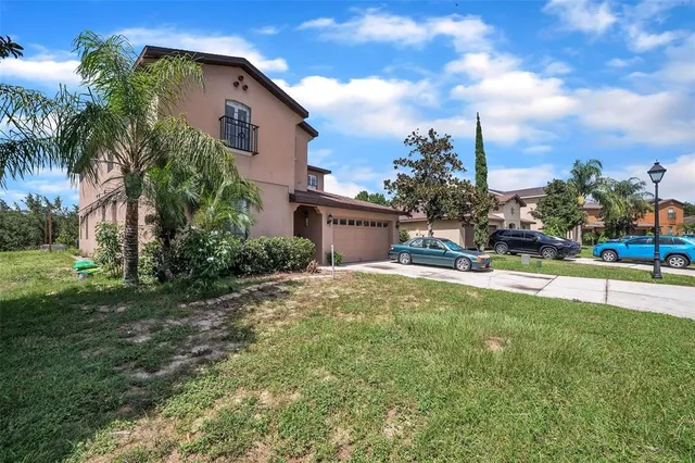 a view of a house with a yard and palm trees